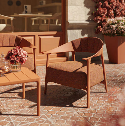 Gros plan sur un fauteuil Africa Vondom clay et sa table basse, fleurs en pot, pavage ocre