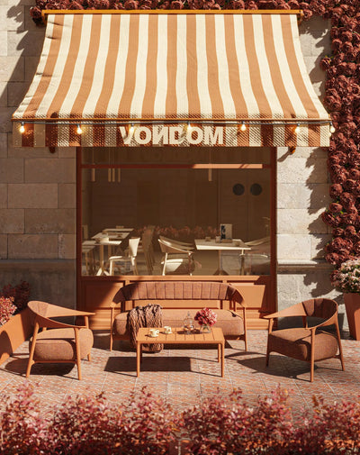 Fauteuils et canapé Africa Vondom clay avec table basse sous un store rayé, terrasse de restaurant