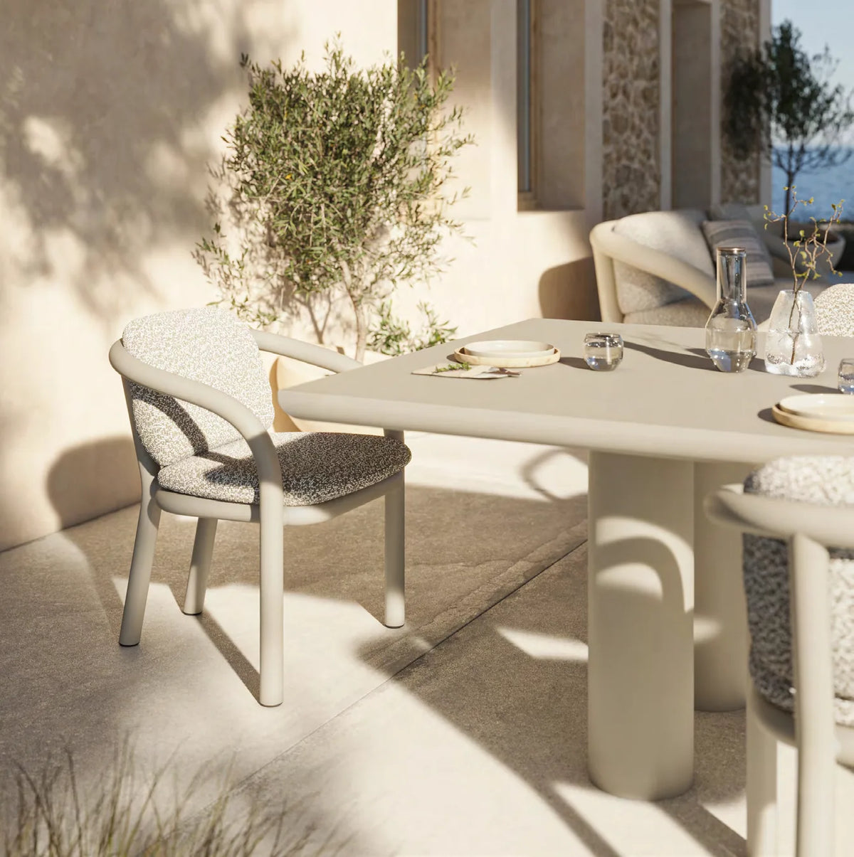 Gros plan sur une chaise Gum écrue avec coussin et la table à manger, couverts dressés
