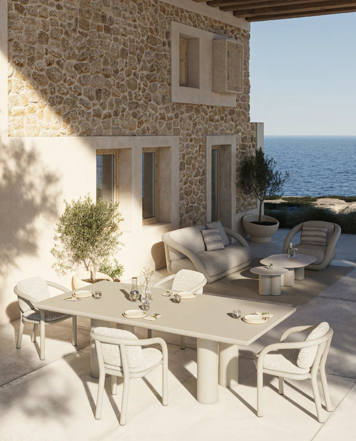 Chaises et table à manger Gum écrues sur une terrasse en pierre face à la mer