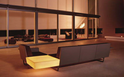 Salon de jardin d'angle Delta Vondom de nuit dans un séjour vitré, table d'angle lumineuse, coque et coussins foncés