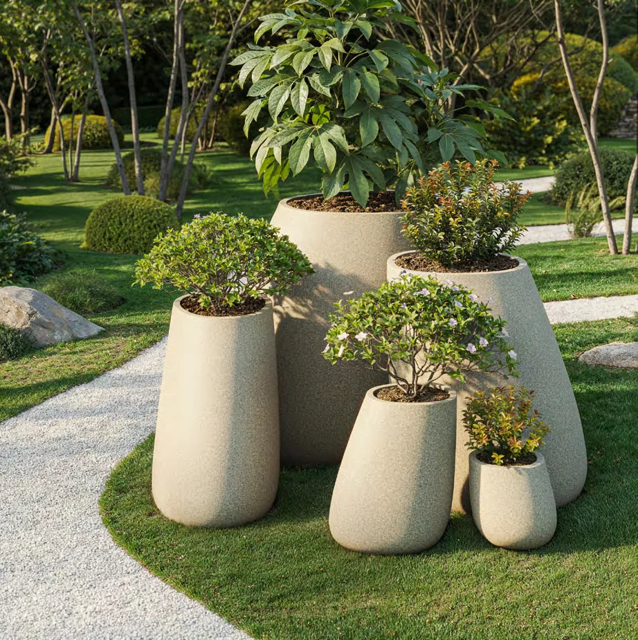 Pots Stone Vondom hauts et bas en granit écru plantés, au bord d'un chemin de gravier