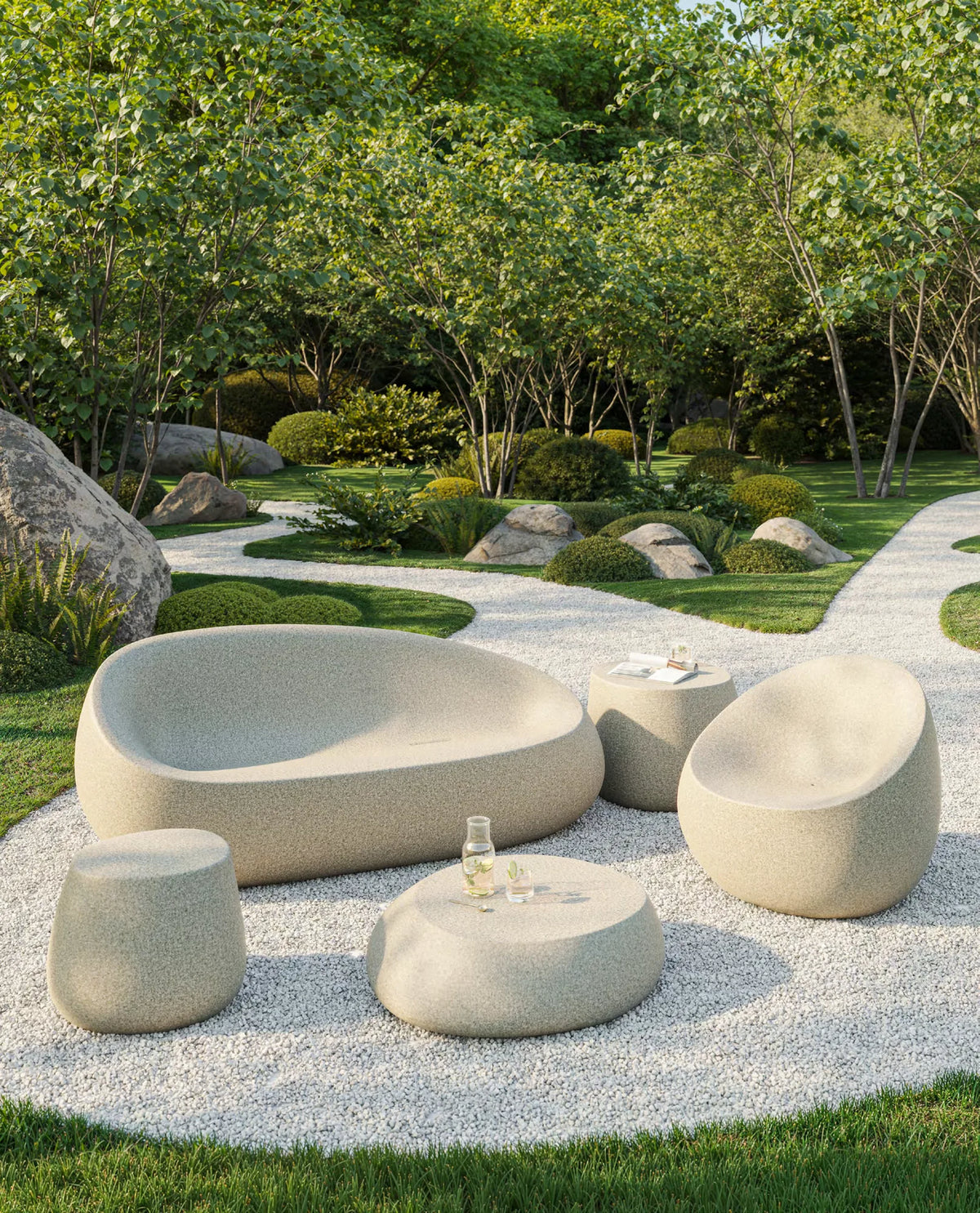 Canapé, tables basses, pouf et fauteuil Stone Vondom en granit écru sur un chemin de gravier blanc