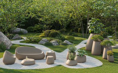 Jardin avec chemin de gravier : fauteuil, canapé, table basse, table d'appoint, pouf et pots Stone Vondom taupe