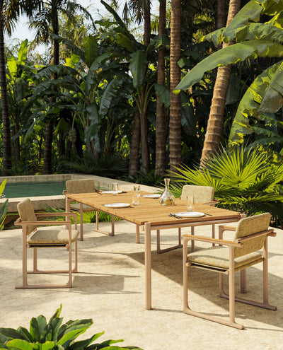 Chaise Tulum camel et table Tulum en teck sur une terrasse entourée de palmiers